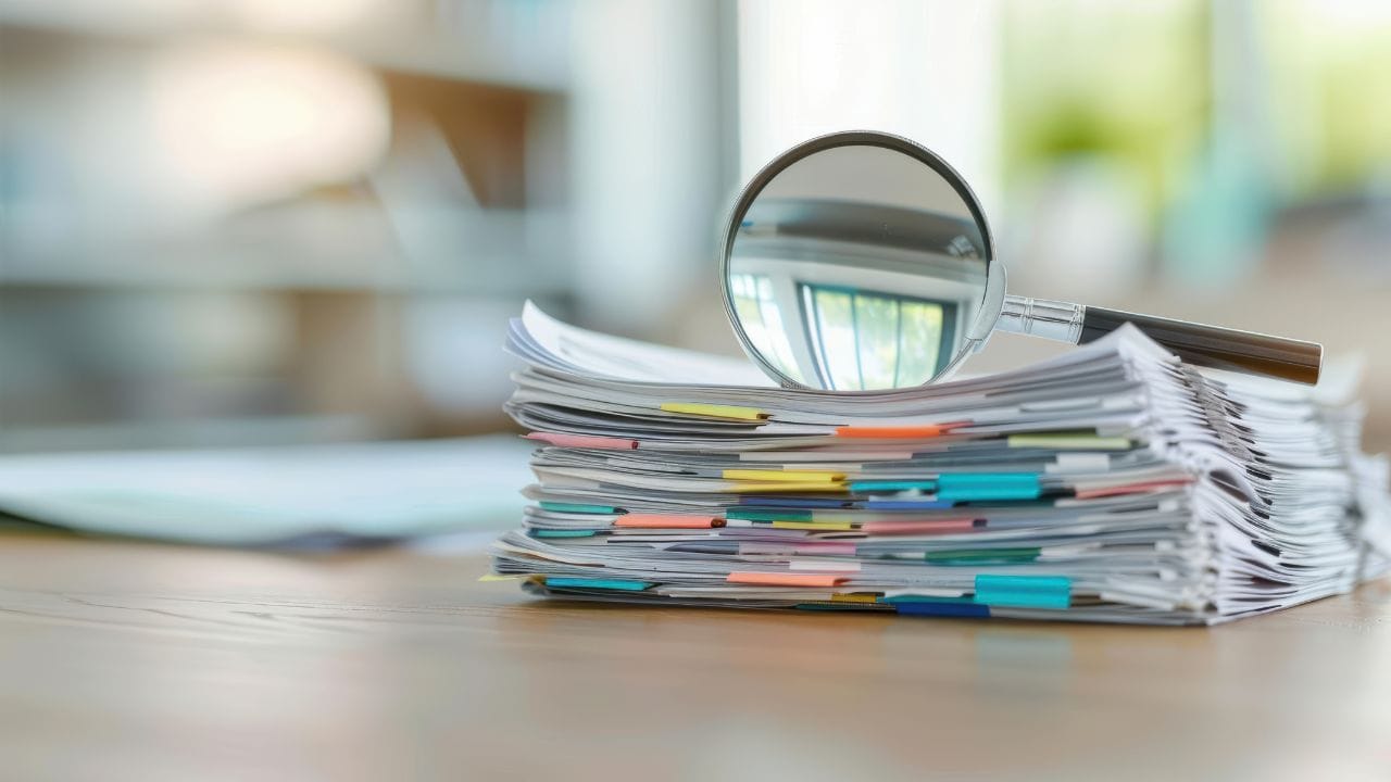 A magnifying glass resting on top of a report folder.