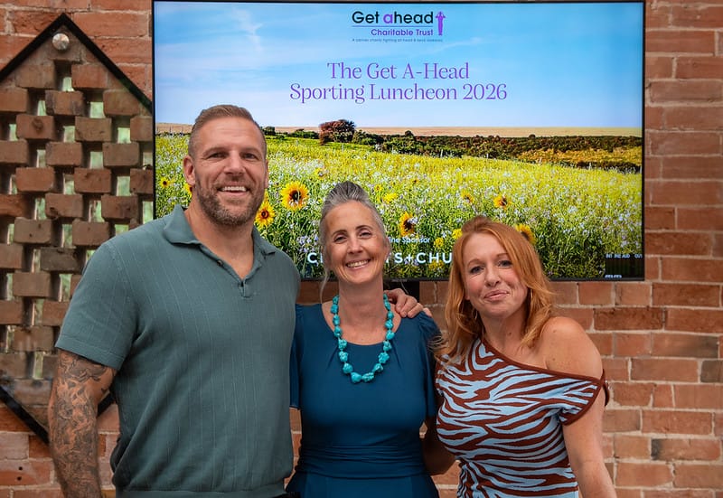 Image of three people standing in front of a PowerPoint slide at event